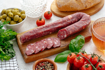 smoked sausage on a wooden board tomatoes and olives