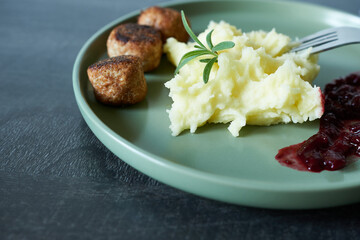 Mashed potatoes with meatballs and cranberry sauce on a plate