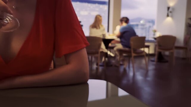 Lonely woman in red drinking wine in bar, happy couple behind