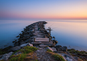 Stone Pier with Fishing Rods at Sunset – Serene Lakeside Horizon