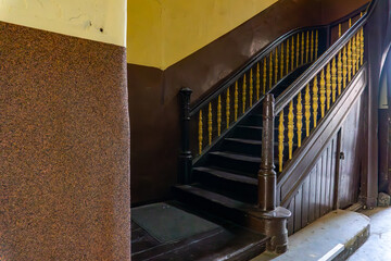 Staircase in an old tenement house with wooden steps and yellow balustrade, element of historic...