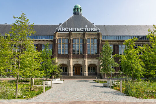 The impressive Faculty of Architecture building at TU Delft, showcasing grand design and surrounded by modern landscaping under a clear sky.