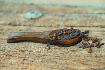 dried cloves in the wooden spoon on wooden background