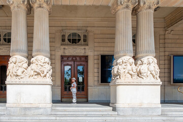 A 10 year old girl, Caucasian, stands at the entrance to the Royal Theatre in Stockholm.