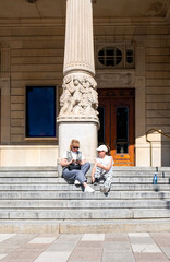 A Caucasian family, a young woman and a 10-year-old girl, sit on the steps of the Royal Theatre in Stockholm.