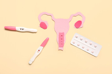 Paper uterus with pills and pregnancy tests on beige background
