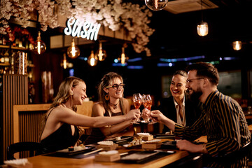 Group of Friends Enjoying Sushi Dinner and Toasting with Drinks in a Restaurant