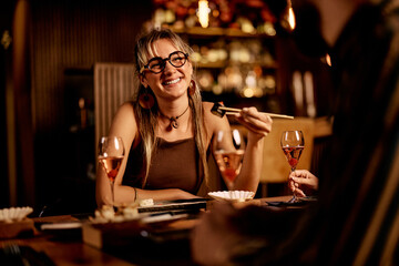 Young Woman Enjoying a Sushi Dinner with Friends in a Cozy Restaurant