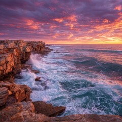 Coastal cliffs meet ocean waves under a fiery sunset sky
