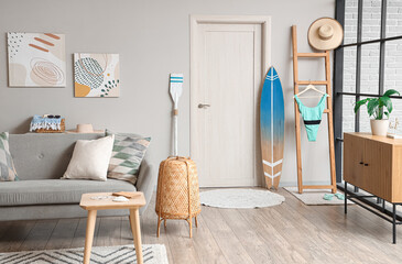 Interior of modern living room with grey sofa and surfboard