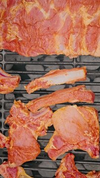 Close-up of raw marinated pork ribs placed on a barbecue grill, ready for cooking over hot charcoal.