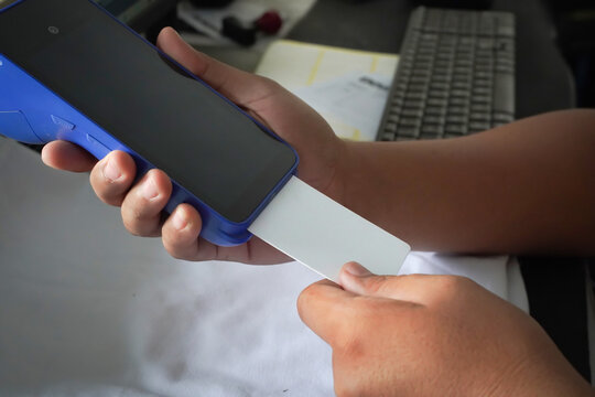 A man is inserting a blank white credit card into an EDC machine. Financial technology mockup.