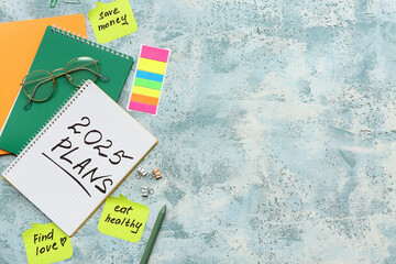 Sticky notes with to do plans, stationery and notebooks on blue grunge background. New year goals...