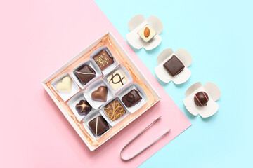 Box with candies and kitchen tongs on color background
