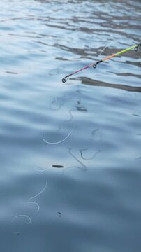 A fishing line is in the water with a hook attached to it. The water is calm and the line is long