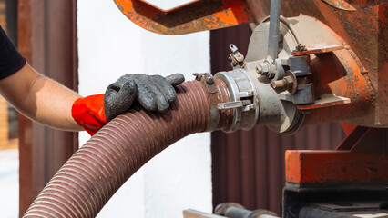 Service worker operates septic tank equipment at country house location in warm weather. Septic tank maintenance.