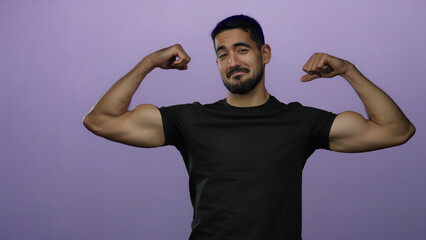 Young man flexing muscles against isolated purple background displaying strength and confidence in...