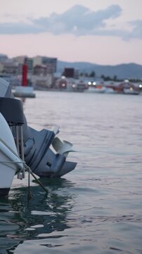 A boat with a motor is sitting in the water. The water is calm and the sky is cloudy