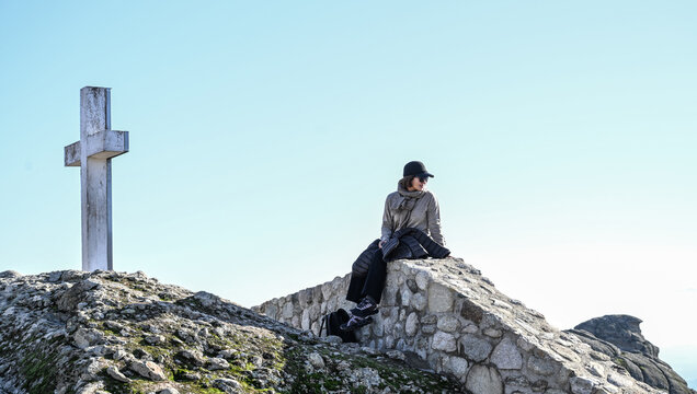 woamn sitting on stonewall at the Meteora monastery