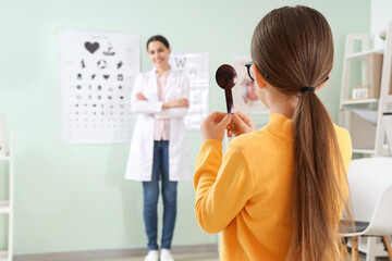 Little girl with occluder checking her eyesight in clinic, back view