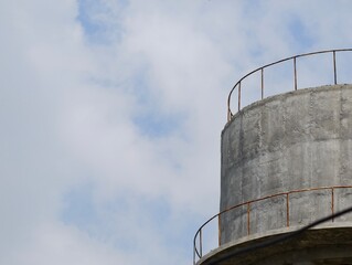 Concrete Water Tower Top with Railing Against Cloudy Sky
