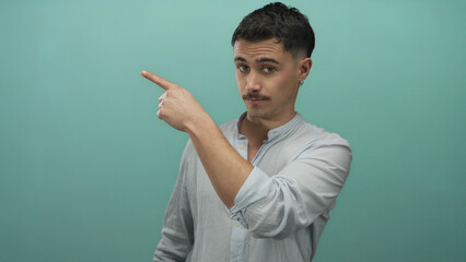 Young hispanic man pointing left against isolated blue background with confident expression...