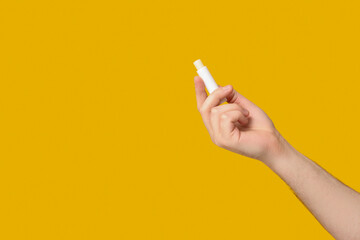Male hand with lip balm on yellow background