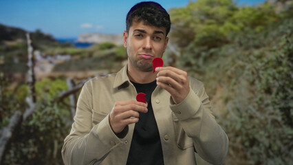 Man grips heart then tears it outdoors as hispanic young male looks sad over heartbreak...