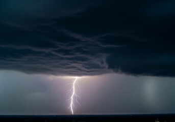 A striking photograph of a single lightning bolt descending from a dark, foreboding cloud. 
