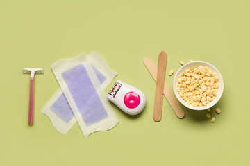 Modern epilator with razor, wax and strips on green background