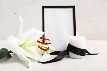 Blank funeral photo frame, candle and white lily on light background
