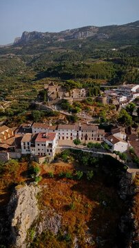 Drone video of the historic hilltop village of Guadalest in Spain, showcasing its ancient castle, charming houses, and surrounding mountains under clear blue skies.
