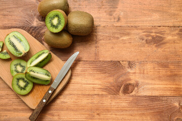 Board with cut fresh kiwi on wooden background