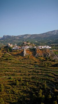 Drone video of the historic hilltop village of Guadalest in Spain, showcasing its ancient castle, charming houses, and surrounding mountains under clear blue skies.