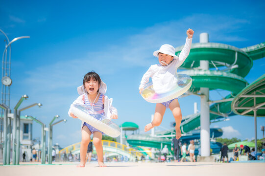 青空の下で元気にプール遊びをする子ども