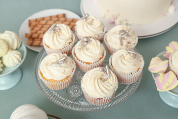 Dessert stand with tasty white cupcakes and other sweets for birthday party on turquoise table, closeup