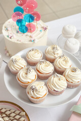 Dessert stand with tasty white cupcakes and other sweets for birthday party on table