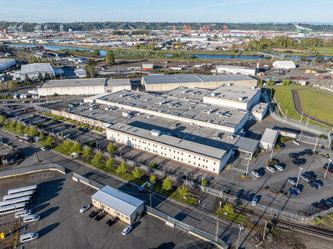 Tacoma, United States - 18 April 2025: Aerial view of the the Northwest Detention Center bathed in the soft glow of the afternoon sun, contrasting sharply with the distant cranes.