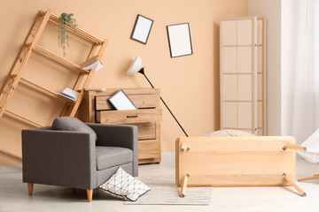 Interior of messy living room with armchair and overturned table