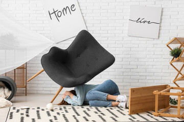 Woman lying on carpet with falling armchair during earthquake at home