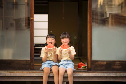 縁側でスイカを食べる女の子