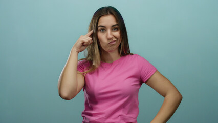 Young woman in pink shirt thinking with puzzled expression against blue wall, encapsulating...