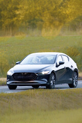 Sporty hatchback car cruising in green landscape