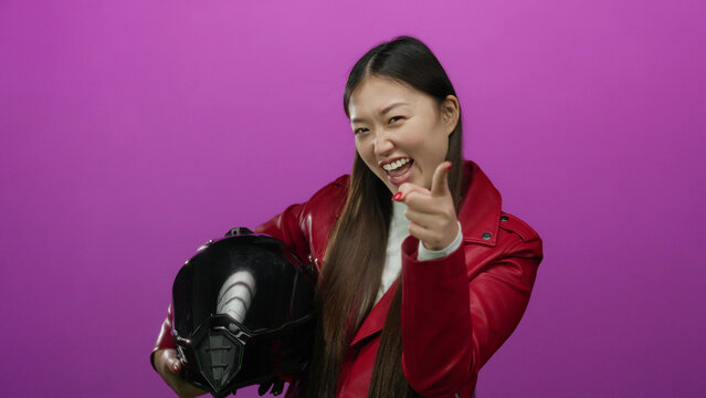 Woman posing confidently in red jacket holding helmet against vibrant pink background showcasing modern style and energy