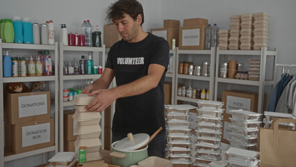 Man organizing food containers in donation room with shelves full of supplies in volunteer setting.