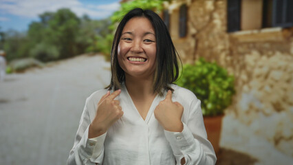 Woman laughing joyfully in a park setting with greenery and rustic backdrop, exuding happiness and positivity during an outdoor experience.