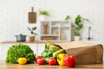 Shopping bag with different fresh vegetables on wooden kitchen counter