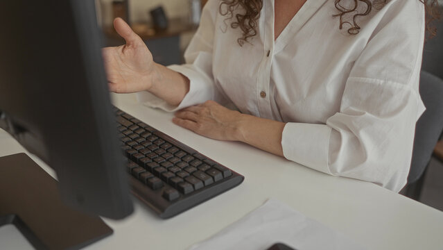 Woman typing on a slim keyboard with fingers poised on a white desk in an office building; efficiency productivity focus.