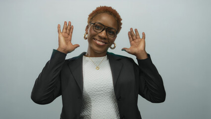 Young african american woman wearing glasses and blazer covering eyes with her hands in light gray...