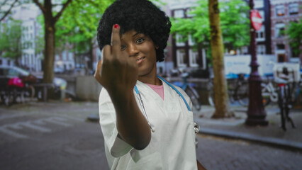 Woman doctor wearing lab coat and stethoscope shows middle finger in city street; defiance...